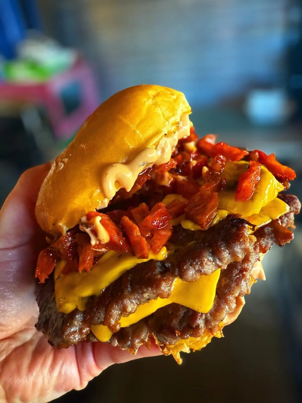 A loaded smash burger from Crumbs & Grind — double patty, melted American cheese, crispy bacon, and house sauce — the kind of food people photograph before they eat